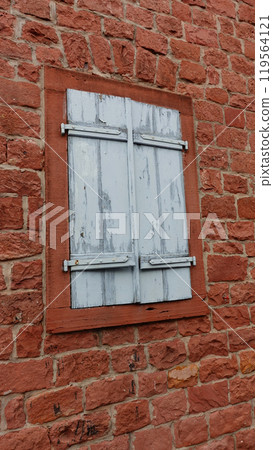 Weathered Wooden Shutters on a Rustic Brick Wall in an Old Building 119564121
