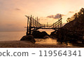 A wooden bridge spans a serene water body at sunset 119564341
