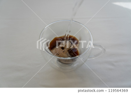 Pouring boiling water into a glass mug with instant coffee. Coffee time Pouring boiling water into a glass mug with instant coffee. Coffee time 119564369