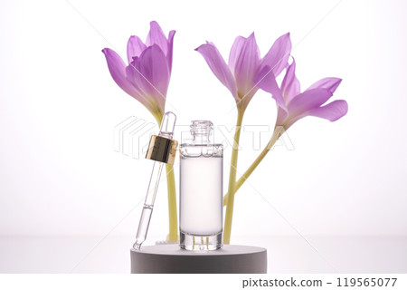 Serum bottle with dropper on light background with purple flowers. Serum bottle with dropper on light background with purple flowers. 119565077