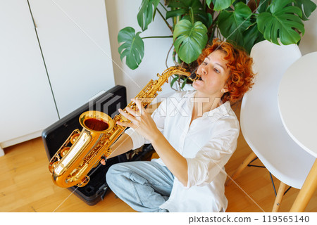 portrait young red-haired attractive woman playing saxophone, 119565140