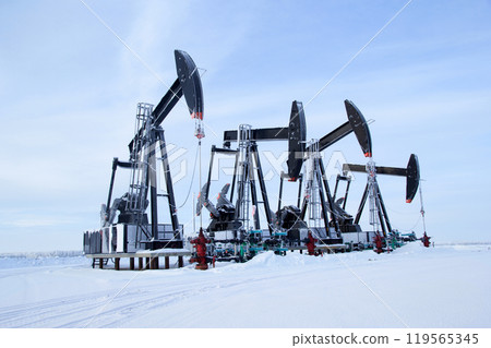 Winter snowy field in prairies and black pump jacks pumping oil. Winter snowy field in prairies and black pump jacks pumping oil. 119565345