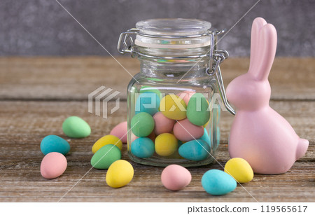 Easter composition with pink bunny and a jar with colorful candies. Easter composition with pink bunny and a jar with colorful candies. 119565617