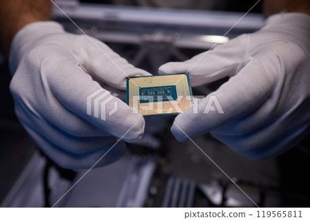 Cropped image of an engineer showing a computer microchip on the foreground 119565811