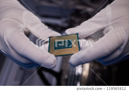 Cropped image of an engineer showing a computer microchip on the foreground 119565812