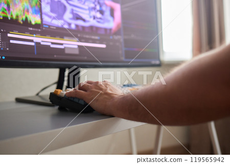 back view of young man in the dark studio color grading video with laptop and external monitor 119565942