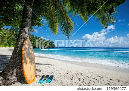 Bright surfboard leaning against a palm tree on a sandy beach overlooking the sea 119566077