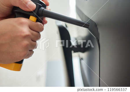 Young man cleaning the inside of a computer with compressed air duster Young man cleaning the inside of a computer with compressed air duster 119566337