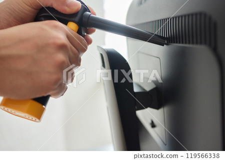 Young man cleaning the inside of a computer with compressed air duster Young man cleaning the inside of a computer with compressed air duster 119566338
