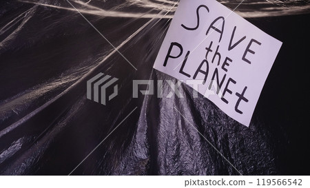 Save planet. Plastic pollution. Ecology problem. Banner with environmental slogan on wrinkled polyethylene film texture dark background. Save planet. Plastic pollution. Ecology problem. Banner with environmental slogan on wrinkled polyethylene film texture dark background. 119566542