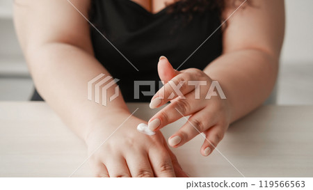 Hand treatment. Skin care. Cosmetic dermatology. Unrecognizable overweight woman fingers applying smearing cream lotion product on light free space. 119566563