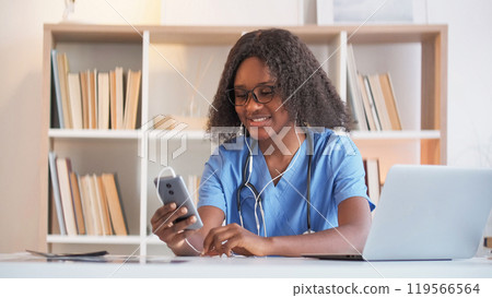 Video consultation. Telemedicine call. Online healthcare. Cheerful woman doctor talking on smartphone telehealth app at clinic modern office. 119566564