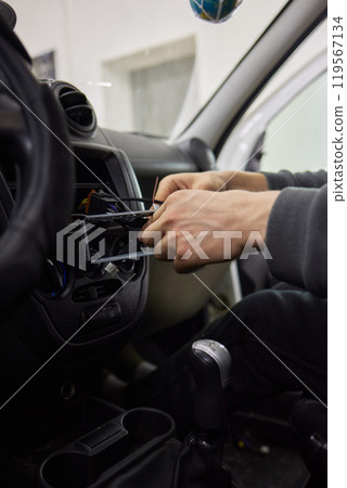 Individual is performing maintenance on the vehicles dashboard 119567134