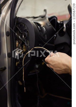 Individual is performing maintenance on the vehicles dashboard 119567139