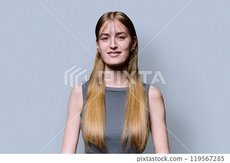 Portrait of beautiful young girl with long blond hair looking at camera on grey background Portrait of beautiful young girl with long blond hair looking at camera on grey background 119567285