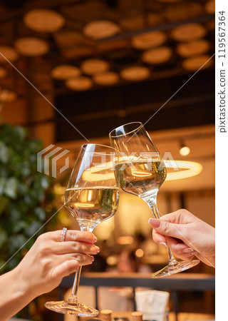 A woman holds a cocktail in her hand, with her fingers wrapped around the glass 119567364