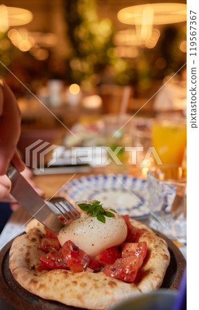 Person preparing bruschetta with tomatoes, egg on a pizza with tableware Person preparing bruschetta with tomatoes, egg on a pizza with tableware 119567367