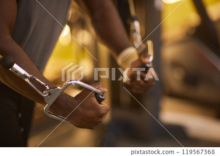 A detailed view of a mans hands in action, controlling a cable machine during workout at the gym 119567368