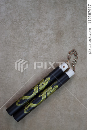 Vertical photography of training nunchucks for self training in use of melee weapons on light background, traditional oriental edged weapons of impact and strangulation type Vertical photography of training nunchucks for self training in use of melee weapons on light background, traditional oriental edged weapons of impact and strangulation type 119567667