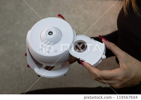 Girl inserts replaceable cartridge with images of planets and stars into galaxy projector for projection onto the ceiling of the room, home planetarium for exploring deep space 119567684
