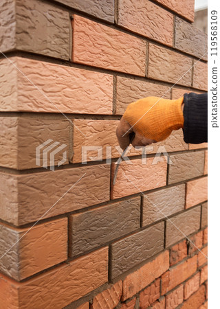 professional construction worker laying bricks and building barbecue in industrial site. Detail of hand adjusting bricks 119568109
