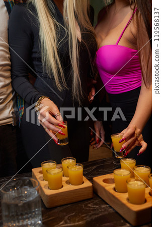Group cheers with shot glasses of Paulaner hefeweizen wheat beer at fun event 119568137