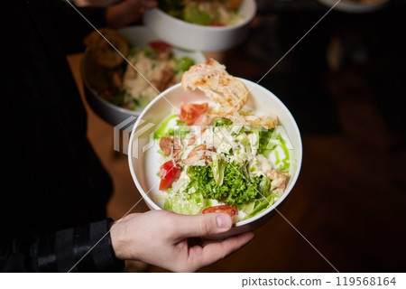 Men's waiter hands hold a Caesar salad Men's waiter hands hold a Caesar salad 119568164