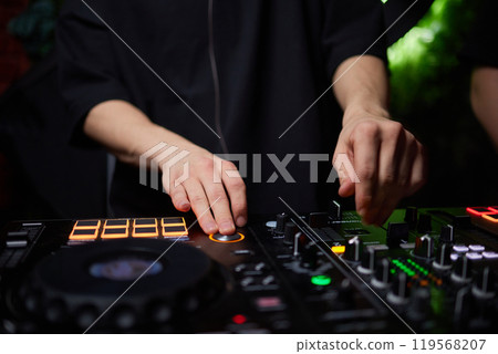 control DJ for mixing music with blurred people dancing at party in nightclub. control DJ for mixing music with blurred people dancing at party in nightclub. 119568207