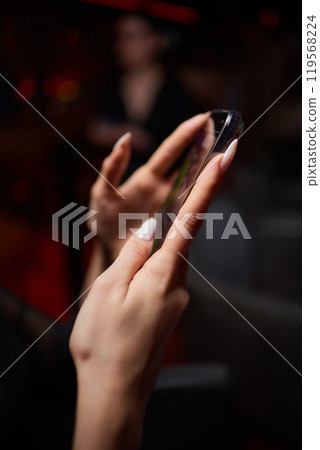 a woman is sitting at a table looking at her cell phone 119568224