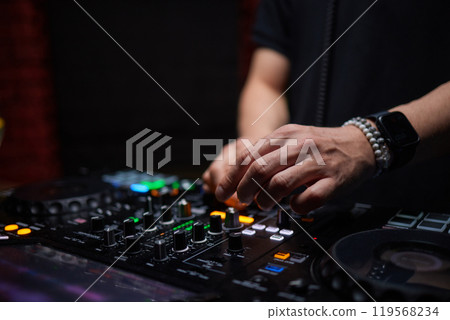 control DJ for mixing music with blurred people dancing at party in nightclub. 119568234