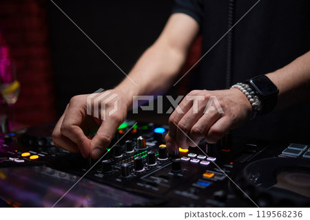 control DJ for mixing music with blurred people dancing at party in nightclub. control DJ for mixing music with blurred people dancing at party in nightclub. 119568236