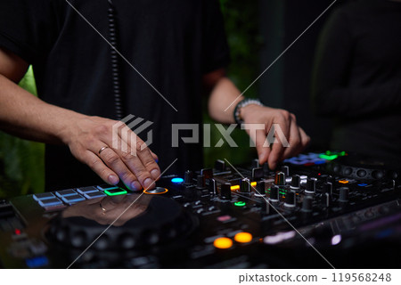 control DJ for mixing music with blurred people dancing at party in nightclub. 119568248