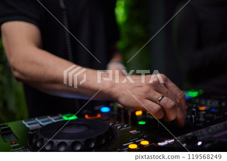 control DJ for mixing music with blurred people dancing at party in nightclub. 119568249