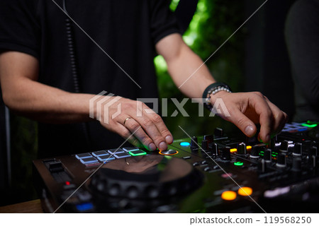 control DJ for mixing music with blurred people dancing at party in nightclub. 119568250