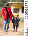 Mother baby in warm clothes standing outdoors in holidays morning sunlight 119568372