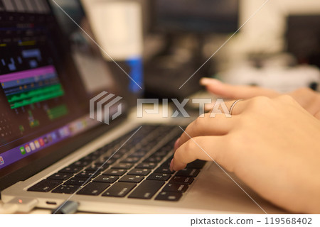 A closeup showing hands typing on a laptop keyboard, with an engagement ring on the finger 119568402