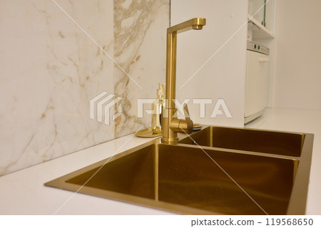 A gold faucet on a bathroom sink with a soap bottle A gold faucet on a bathroom sink with a soap bottle 119568650