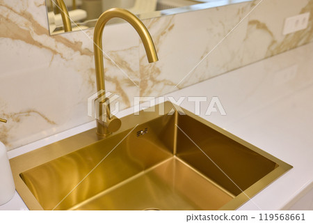 A gold faucet on a bathroom sink with a soap bottle 119568661