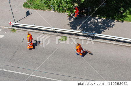 Municipal cleaners manually sweep the city roadway Municipal cleaners manually sweep the city roadway 119568681