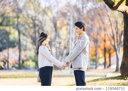 A couple walking in the park enjoying the autumn leaves A couple walking in the park enjoying the autumn leaves 119568731