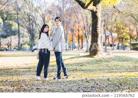 A couple walking in the park enjoying the autumn leaves 119568762