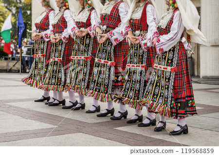 Women dressed in colorful traditional folk costumes dancing in cultural festival 119568859