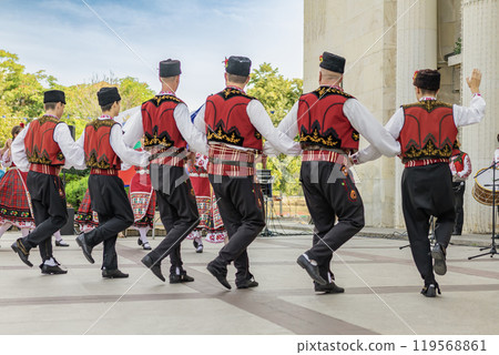 Groups of dancers in colorful traditional attire engage in a lively performance, cultural heritage Groups of dancers in colorful traditional attire engage in a lively performance, cultural heritage 119568861