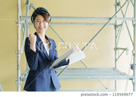 A female businessman looking at a drawing at a construction site (suit, construction, site supervisor, fist pump) 119569077