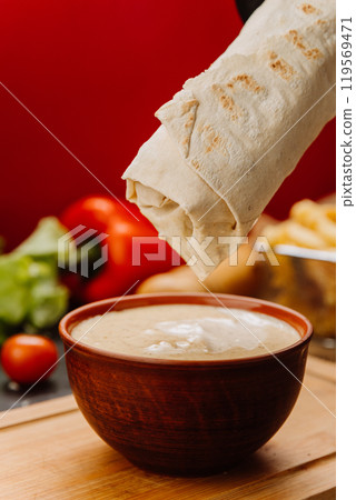 Dipping a wrap into creamy sauce, the perfect blend of flavors for food lovers 119569471