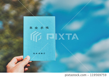 Person holding pension book with blue sky background Person holding pension book with blue sky background 119569759