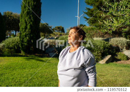 Thoughtful senior woman in sportswear standing at 119570312