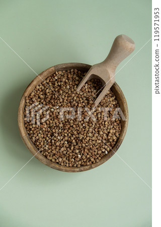 Raw buckwheat porridge in green background copy space. Whole spelt grain species. High protein fiber-rich vegan plant based food ingredient. Gluten free superfood healthy nutritional dietary 119571953