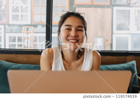 Happy woman enjoy working online remotely from a co-working space cafe. 119574039