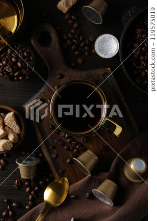 Coffee capsules, coffee beans, and cup on wooden background, top view 119575019